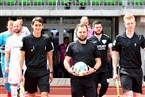 Angeführt von Schiedsrichter Sebastian Wieber (mi.) und seinen Assistenten Nikita Kolodeznyj (li.) sowie Bastian Münch betreten der FC Eintracht Bamberg (weiß) und die SpVgg Selbitz (pink) das Fuchsparkstadion.